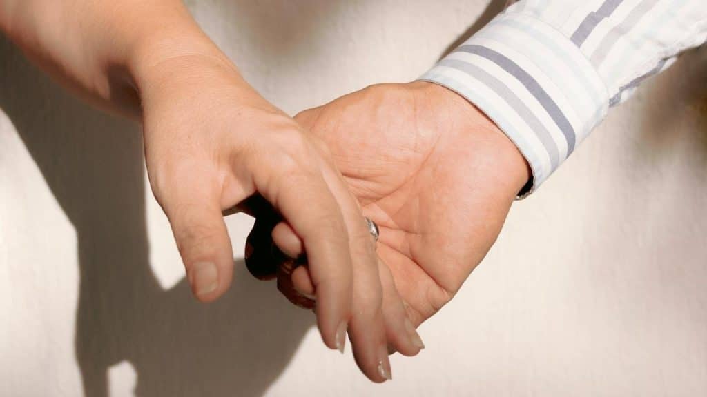 A close-up of two people holding hands gently.