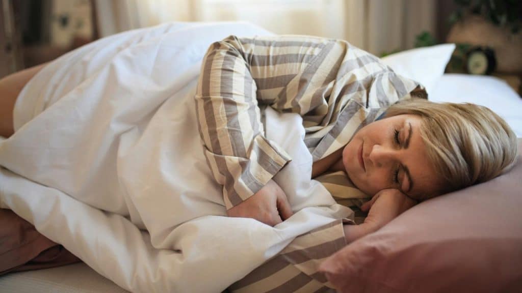 A woman sleeping peacefully in bed with striped pajamas.