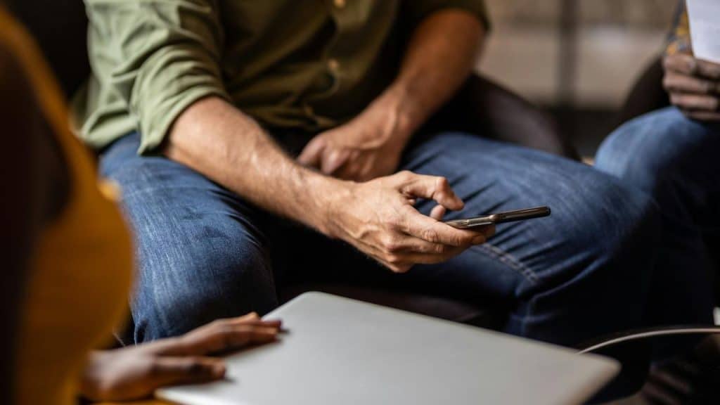 A man holding a smartphone while sitting down.