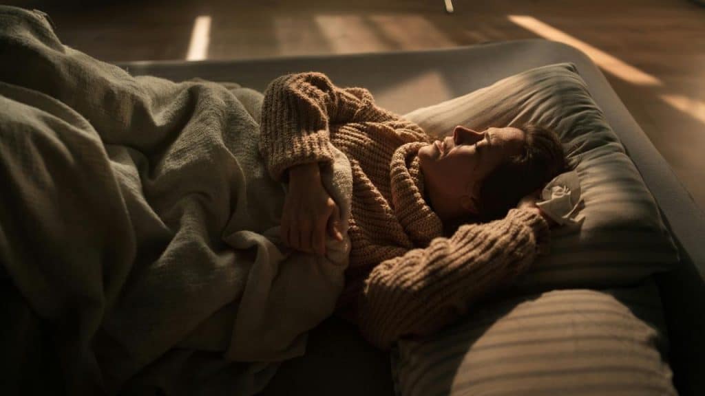 A woman lying in bed resting with a blanket and pillow.