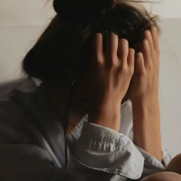 A person sitting with their head in their hands, conveying distress.