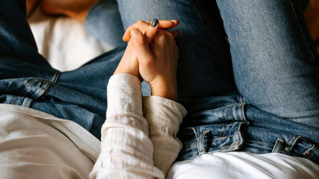A close-up of a couple holding hands while sitting together.