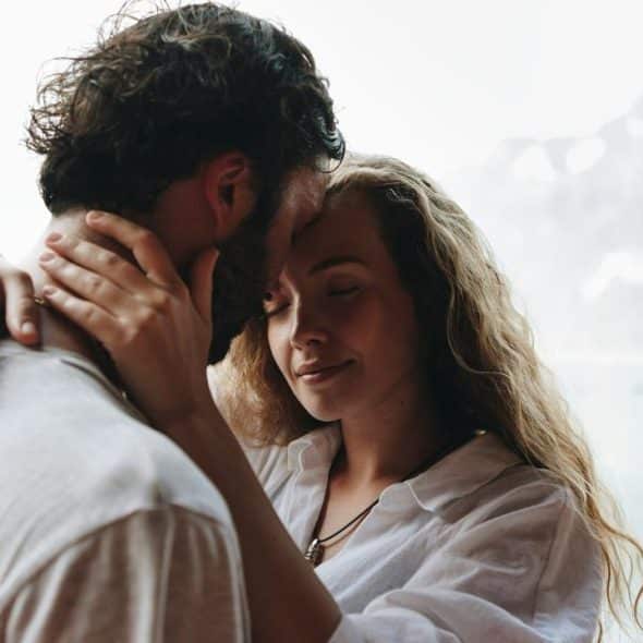 A couple sharing a tender embrace by a lakeside.