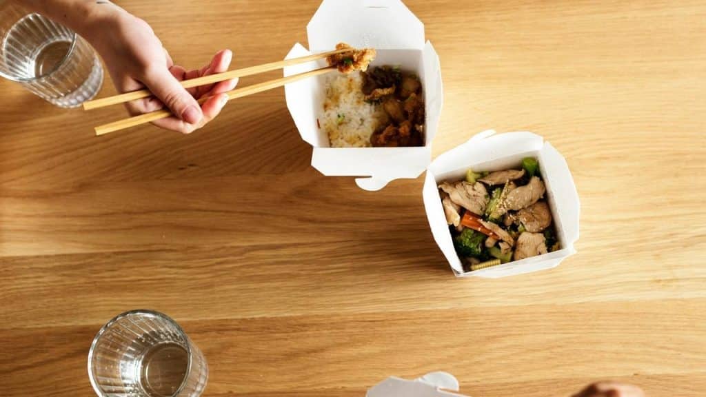 A top view of people eating takeout with chopsticks.