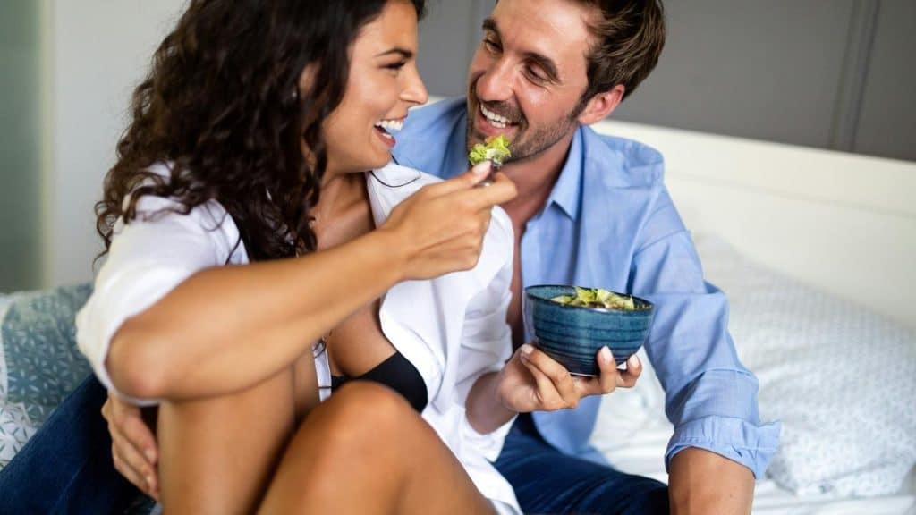 A couple smiling and sharing a meal together.
