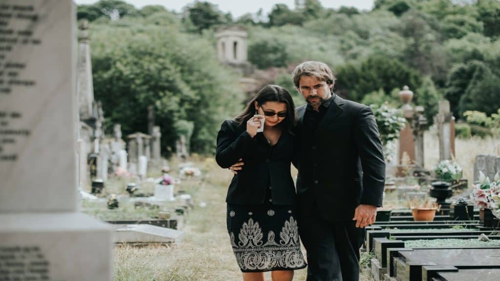 A man supporting his wife at a funeral