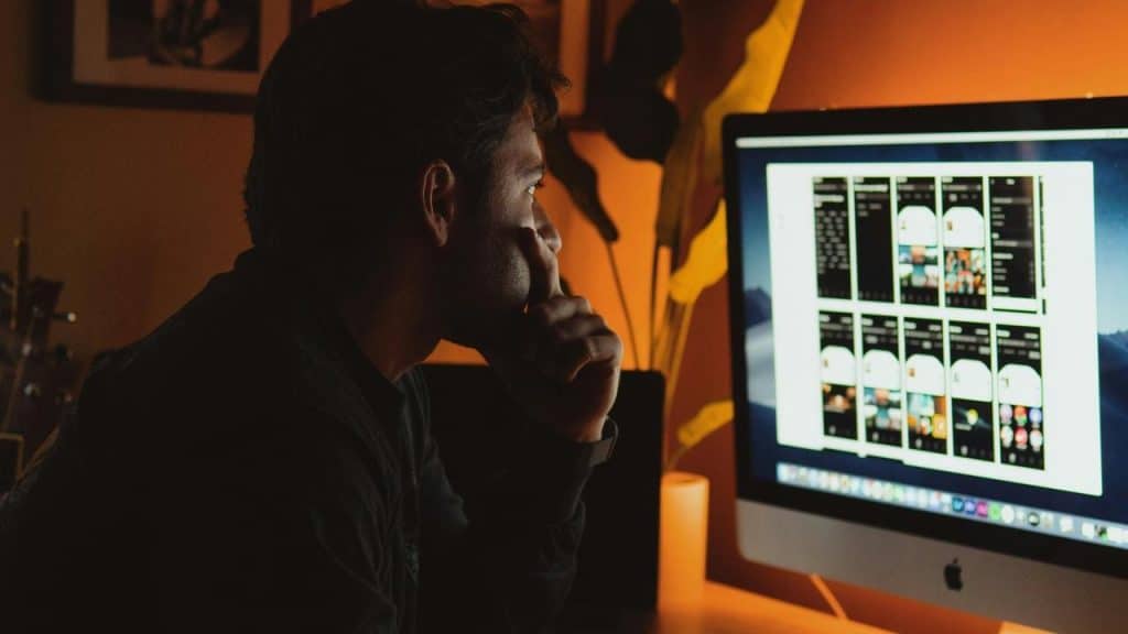 A man looking at a computer screen in a dark room.