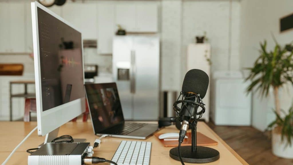 A podcast setup with a microphone, computer, and audio interface on a desk.