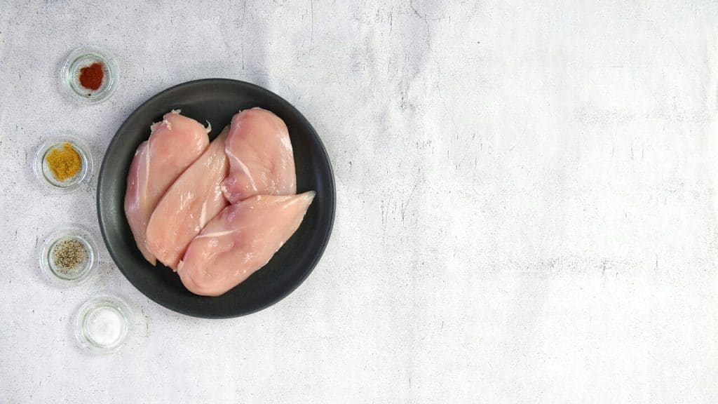 Two raw chicken breasts in a black bowl