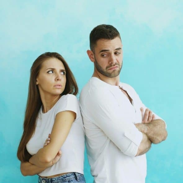 A couple standing back to back and looking awkward