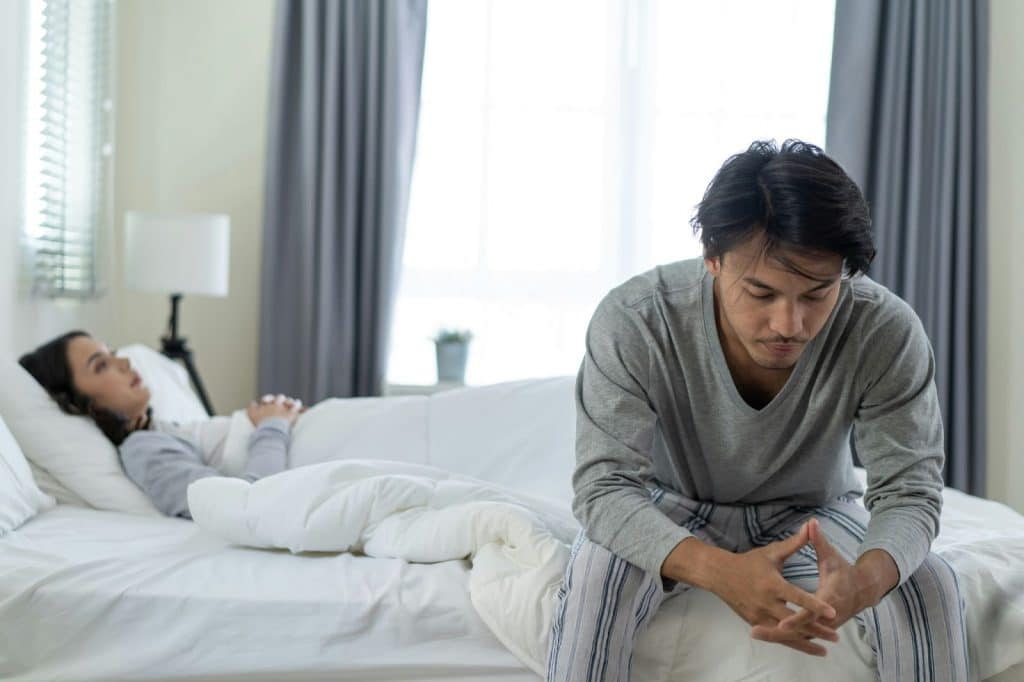 A man sitting at the corner of the bed