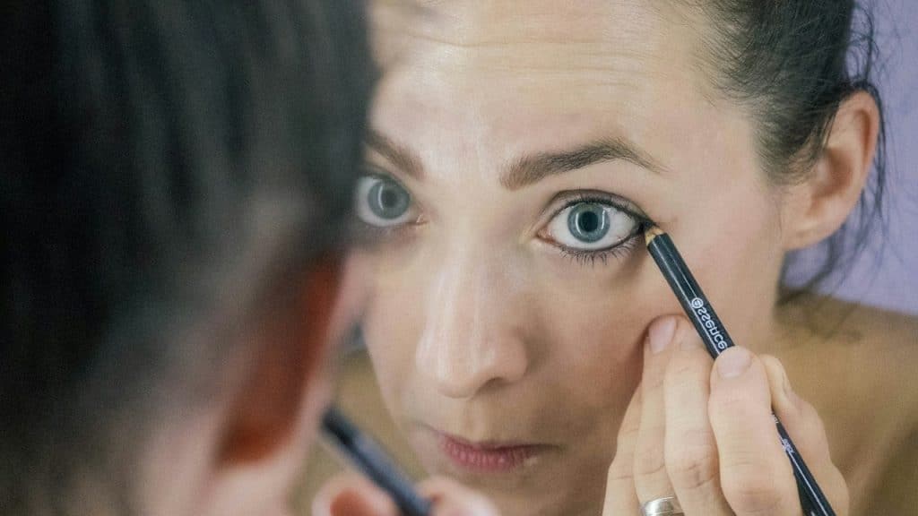 A woman applying eyeliner. 