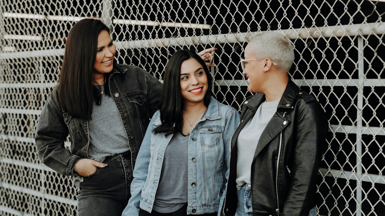 A group of friends smiling and standing by a fence.