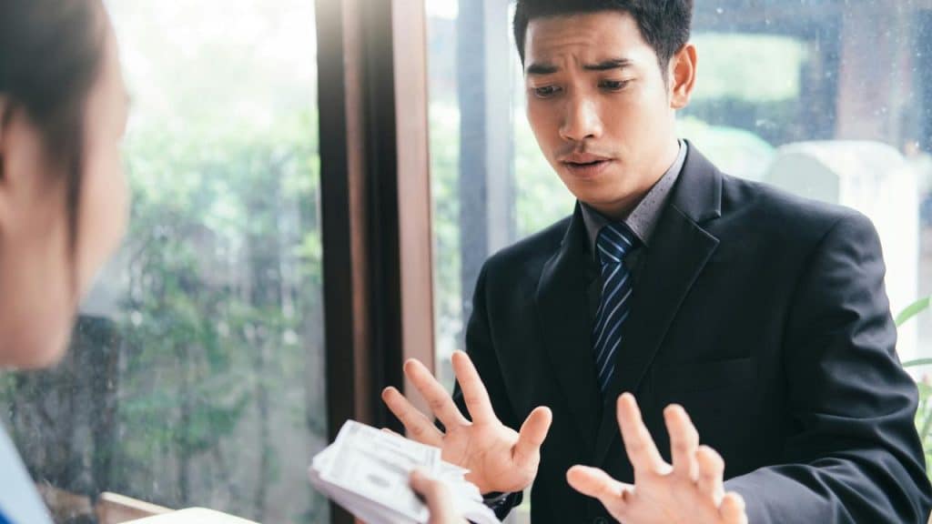 A man in a suit refusing money.