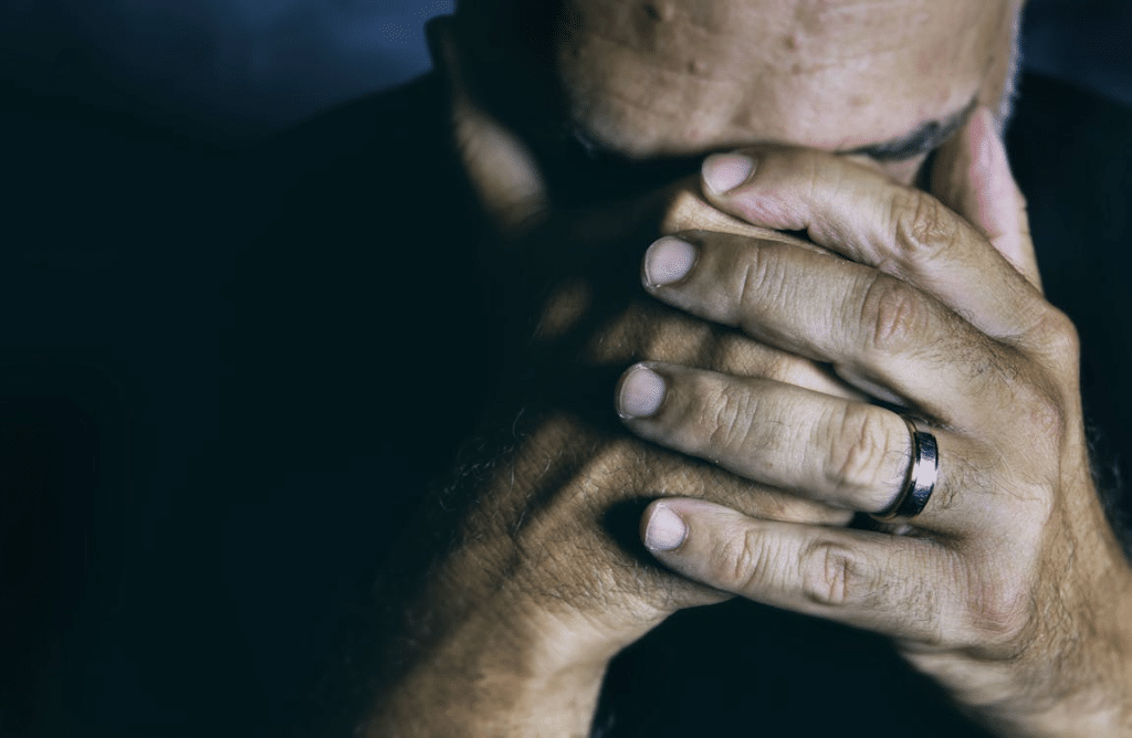 A sad man covering his face