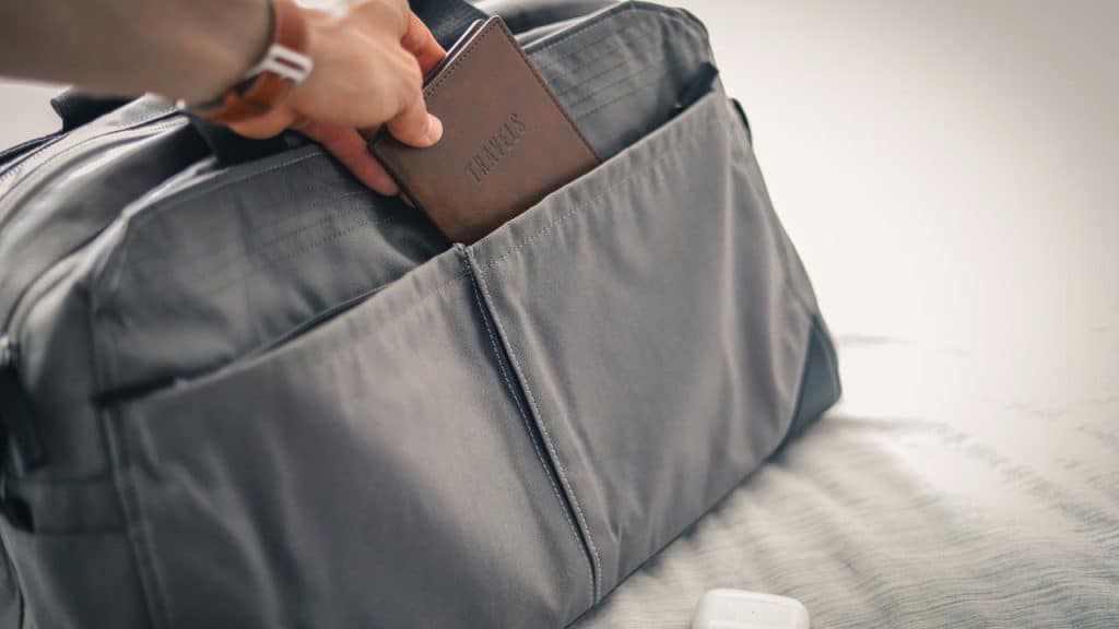 A person putting a travel document into a bag.