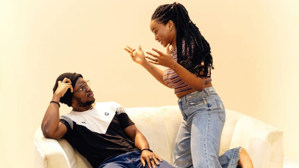 A couple in an argument, with the woman gesturing animatedly while the man looks down in resignation.