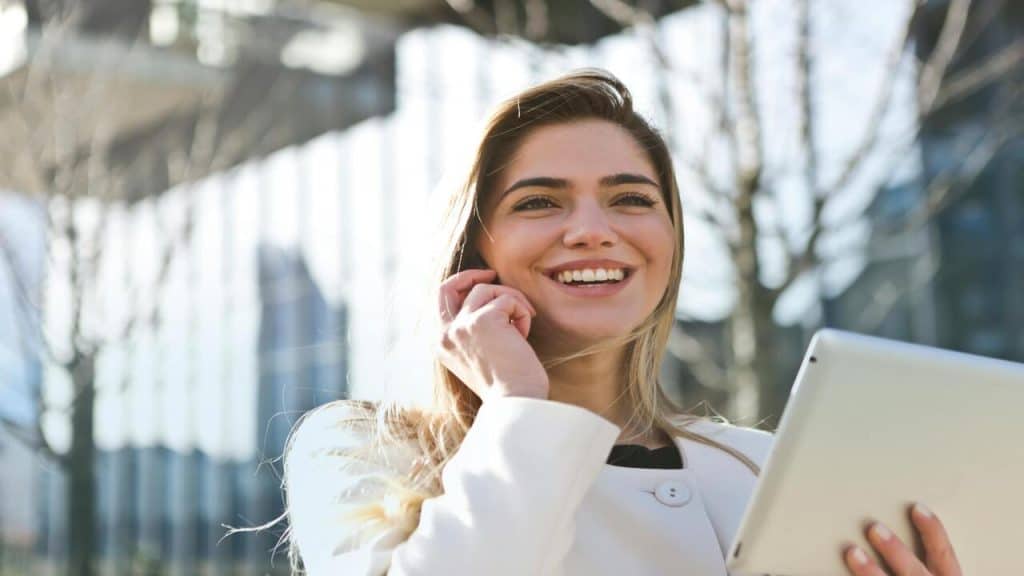 A woman smiling while holding a tablet