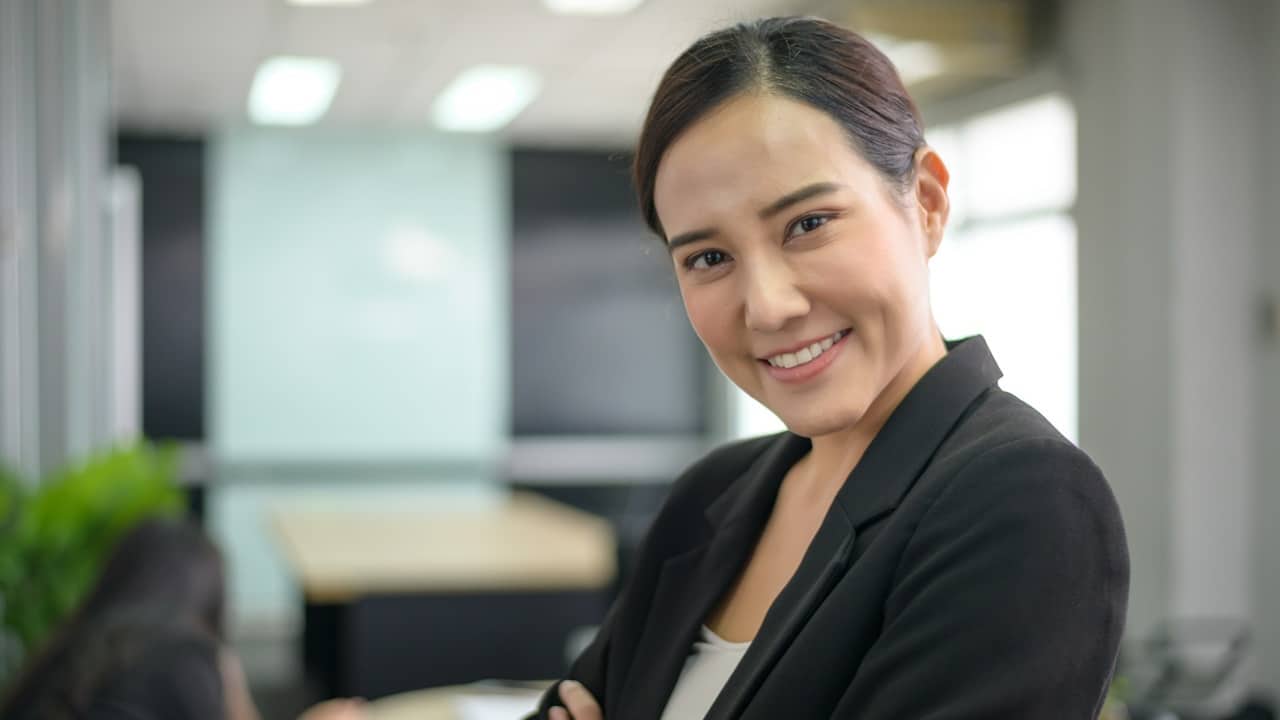 A smiling woman wearing a black dress is posing for a photo.