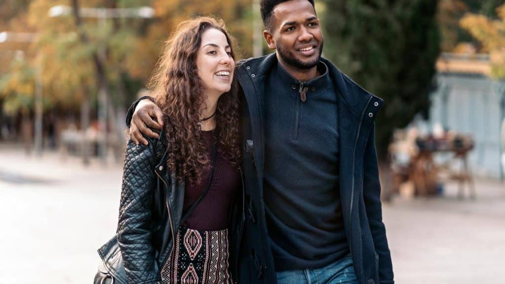 A couple walking arm in arm outdoors, smiling together.