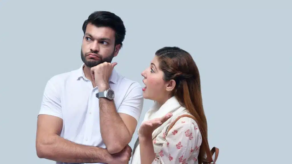 A woman speaks and gestures with her hand while a man beside her looks away.