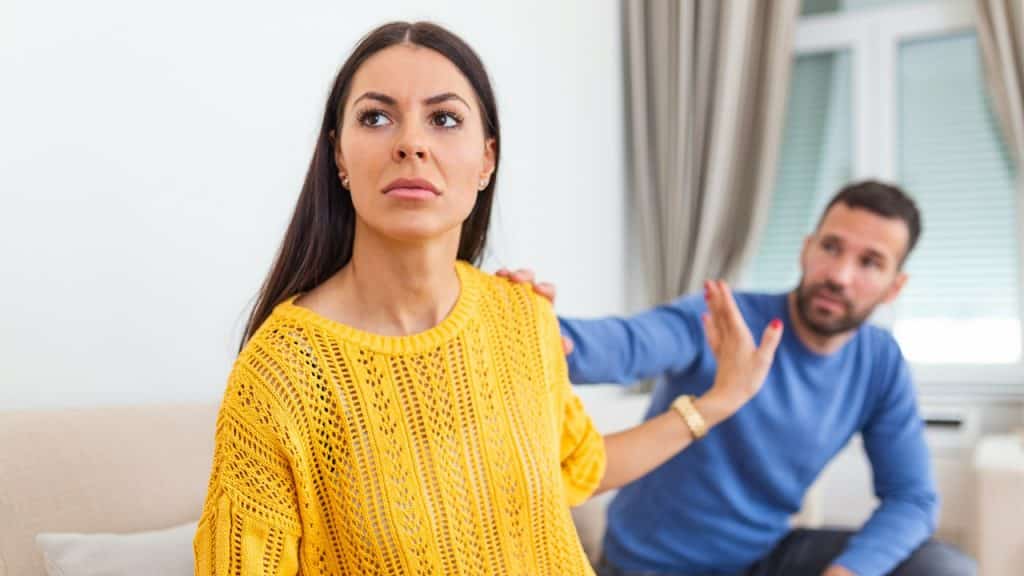 A man saying sorry to his frustrated wife, who is ignoring him.