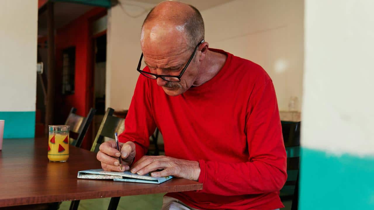 A man writing in a notebook at a table.