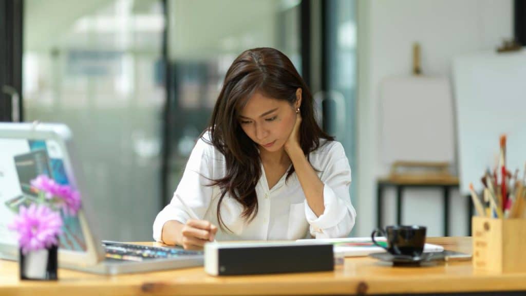 A woman concentrating while working at a desk with a laptop.