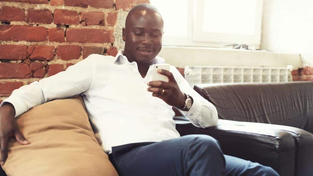 A man sitting on a couch looking at his phone.