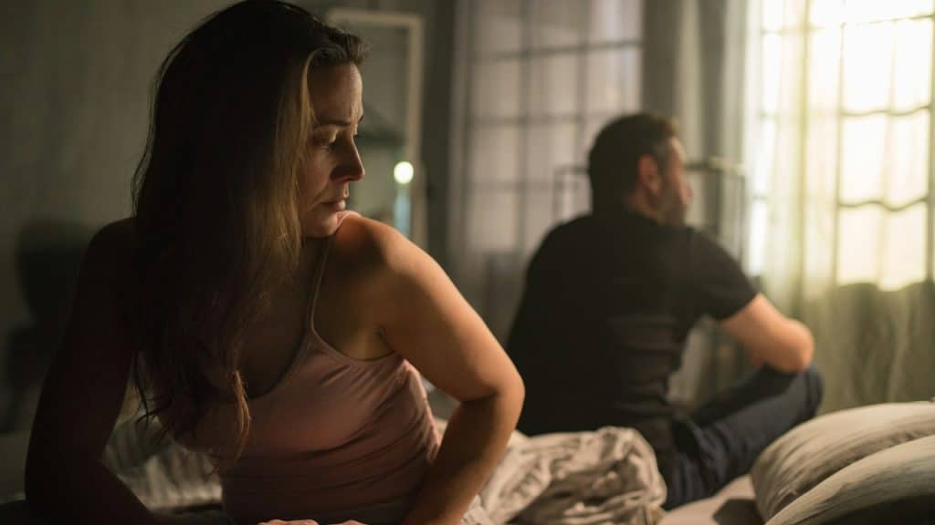 A couple sitting on bed having relationship problems.