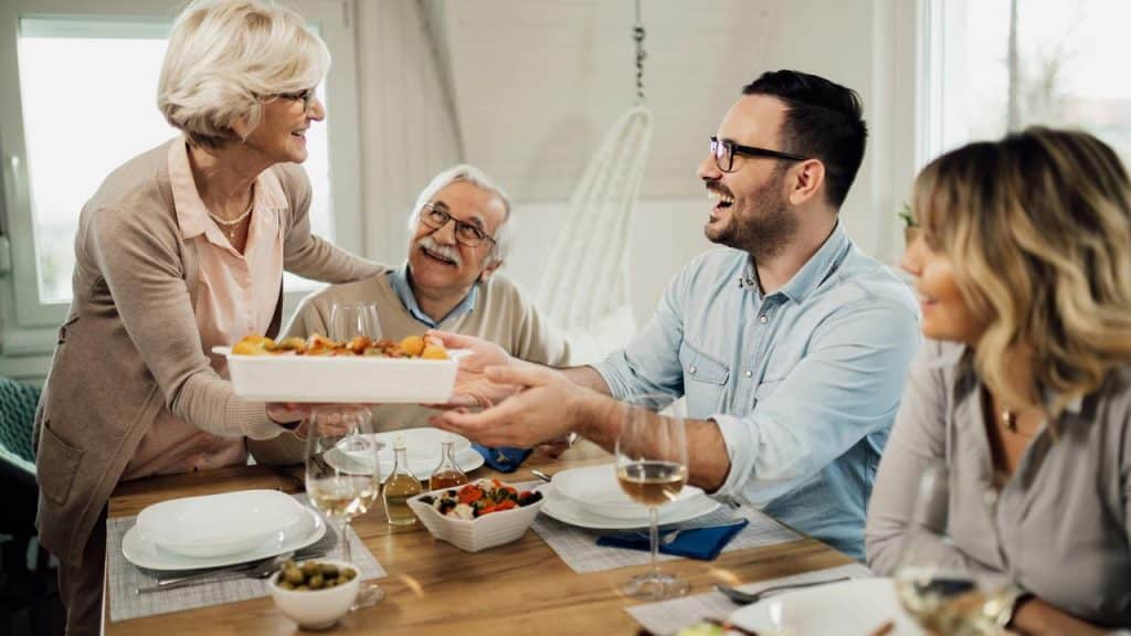 A family smiling and sharing a meal around a dining table.