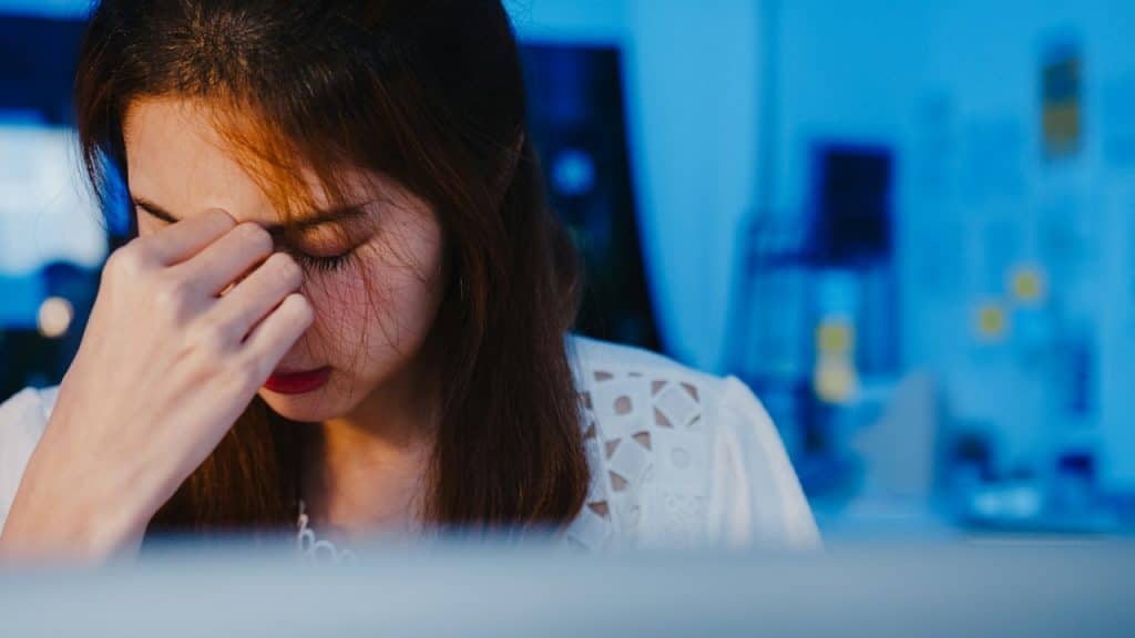 A woman looking anxious and holding her fingers up to her closed eyes.