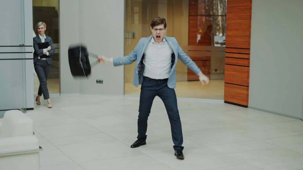 A man throws a briefcase in office frustration.