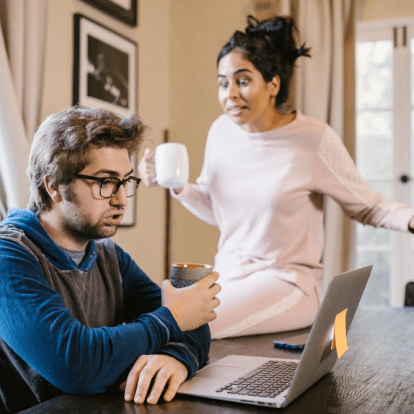 A Man Sitting in Front of a Laptop Beside an Upset Woman
