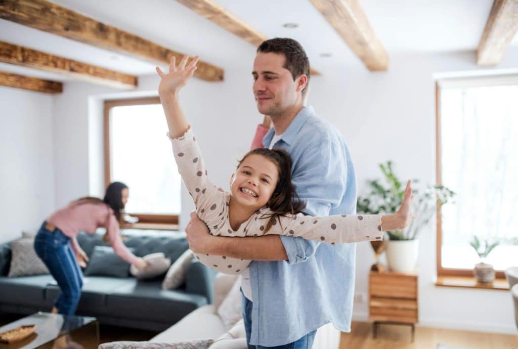 A man carrying a child and a woman fixing their couch