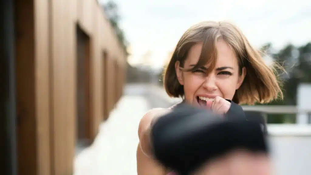 A front view of a young woman practicing karate outdoors on a terrace.