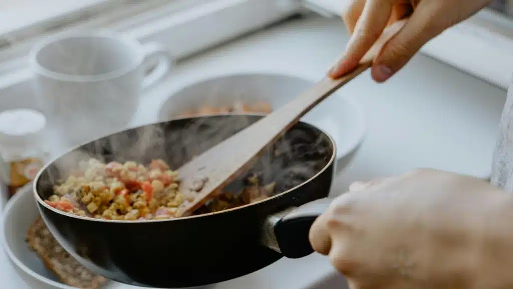 A person cooking vegetables in a pan.