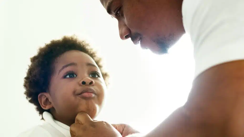 A father helping his child button a shirt.