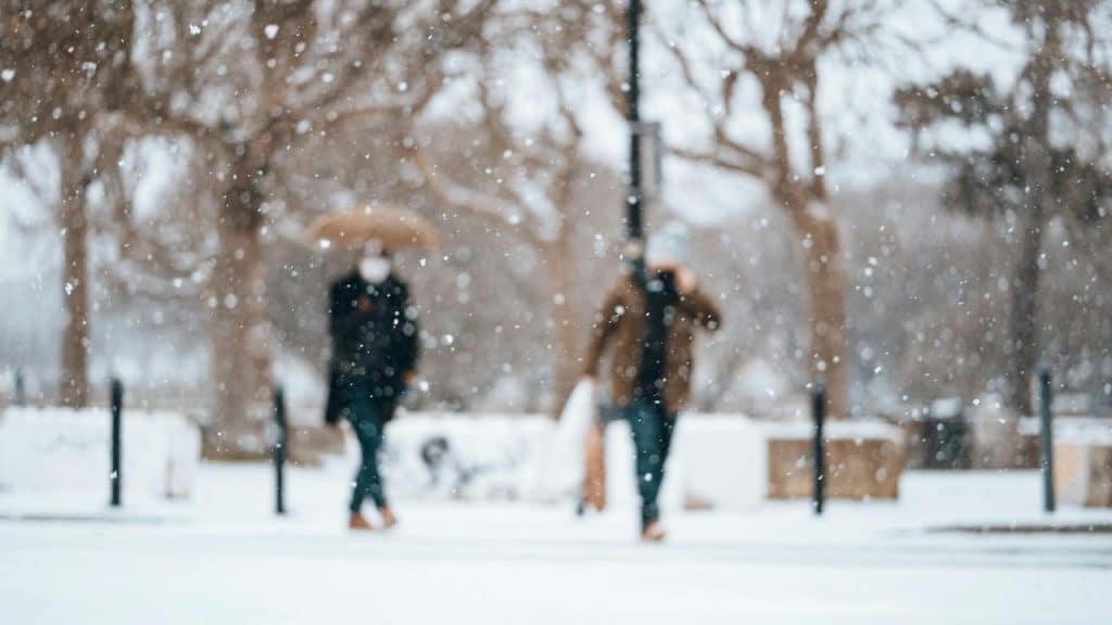 A snowy scene with two people walking.