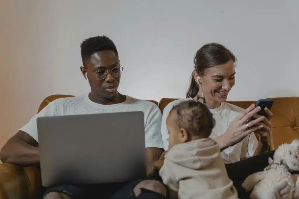 A man looking at the baby while he work 
