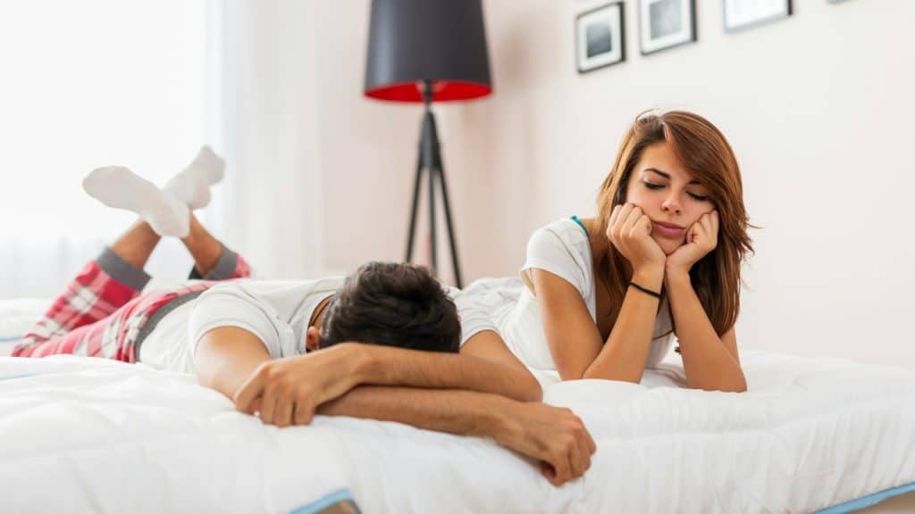 A woman rests her chin on her hands while a man lies face down behind her.