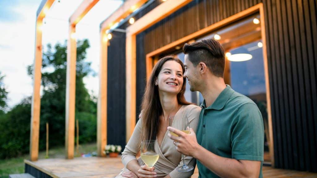 A couple smiling and holding drinks on an outdoor patio.