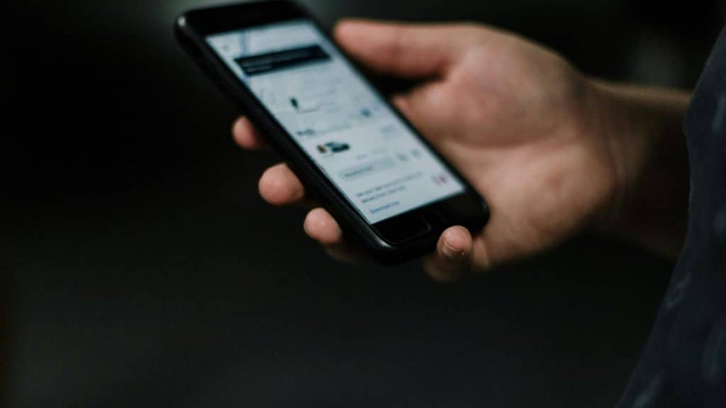A hand holding a smartphone with a blurred screen in low light.