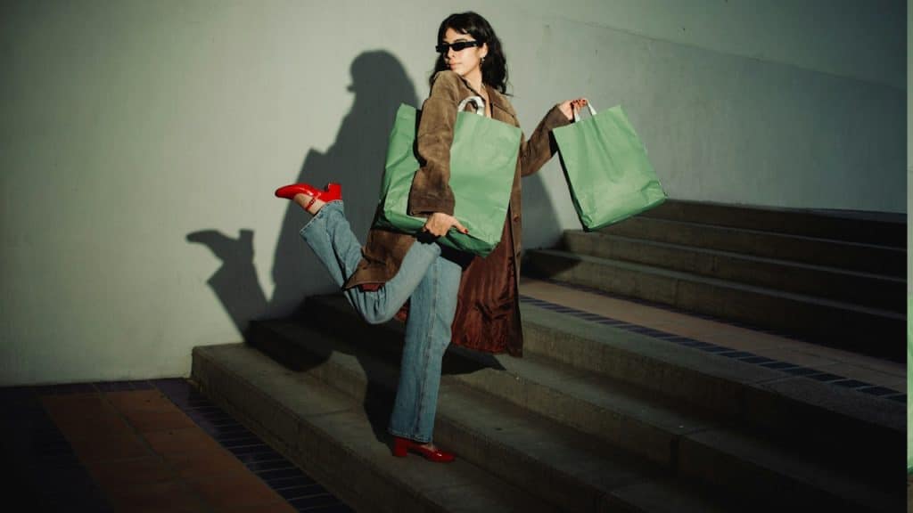 A woman with shopping bags standing on stairs.