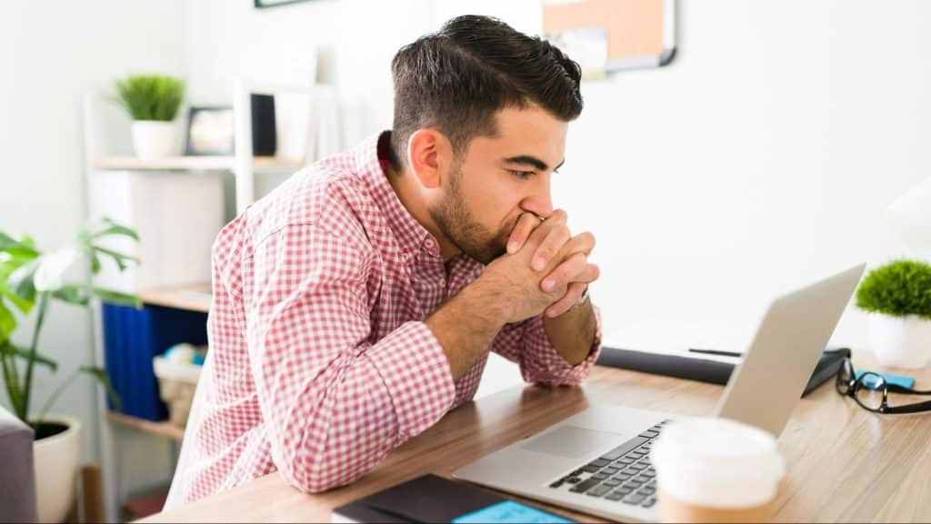 A man looking stressed while looking at the laptop