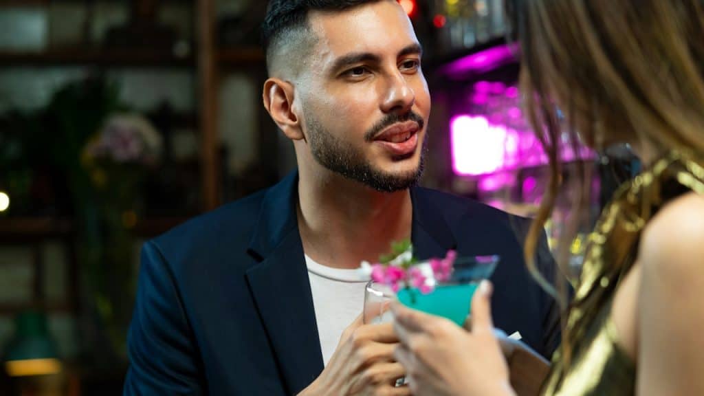 A couple drinking alcoholic cocktails at a bar.