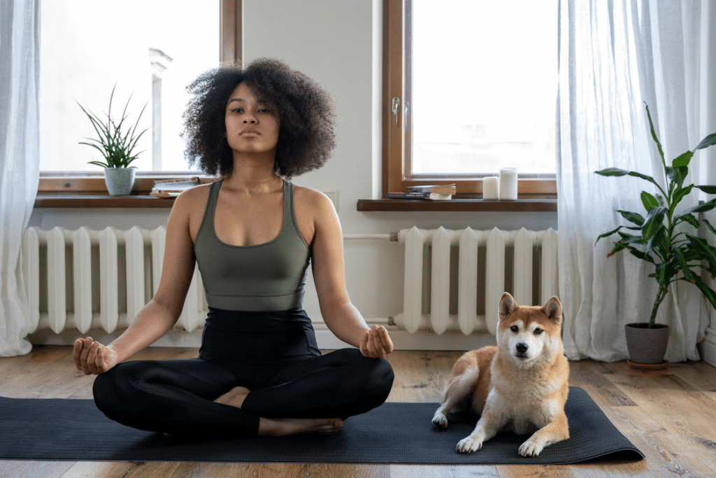 A woman doing yoga on a mat with a dog