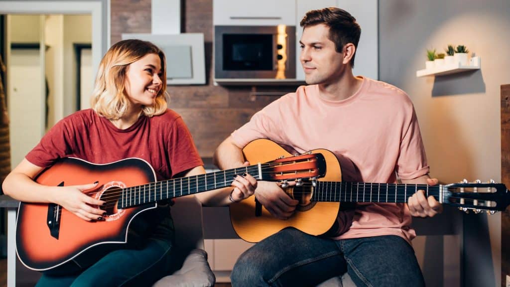 A young couple playing a guitar together.