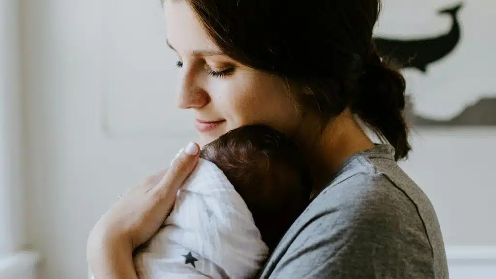 A mother gently holding a sleeping newborn.