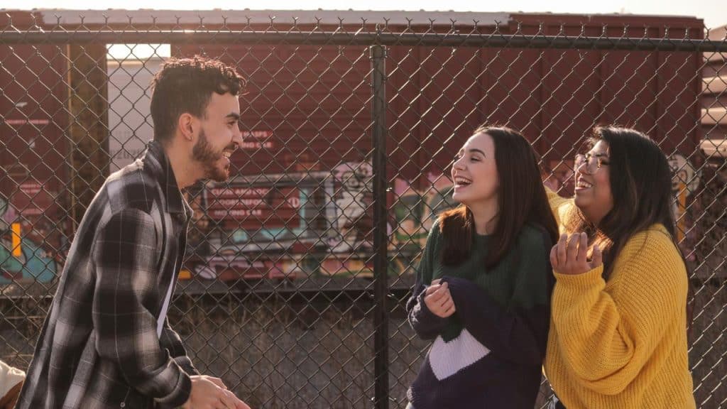 A group of friends laughing near a fence.